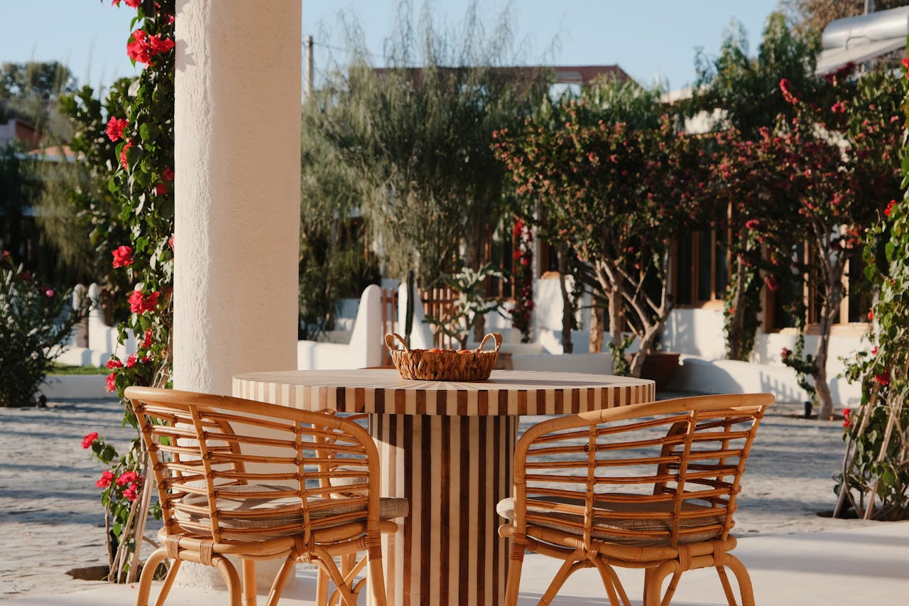 Elegant patio with wicker chairs and table surrounded by vibrant foliage in Aguergour, Morocco.
